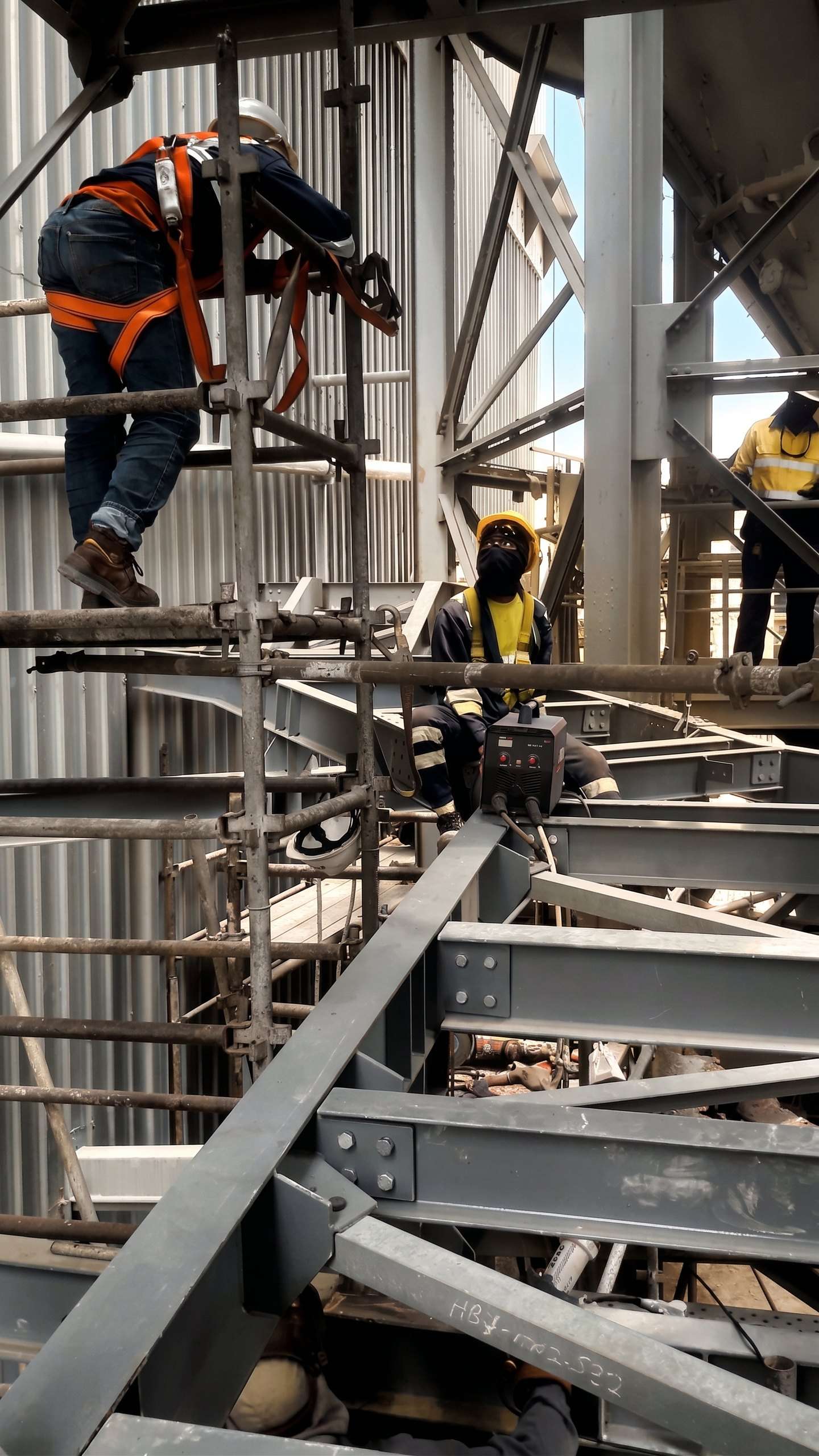 Equipe com equipamentos de proteção montando estrutura metálica