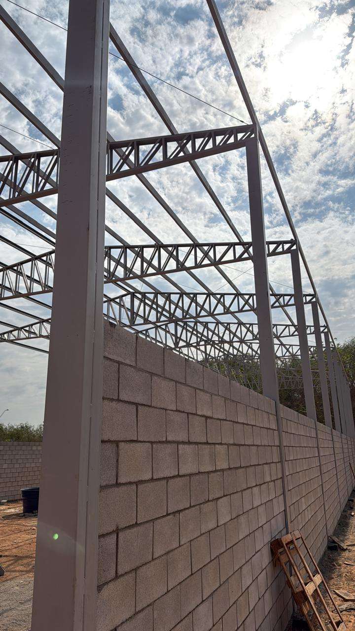 Parede de blocos construída entre pilares e treliças de uma estrutura metálica