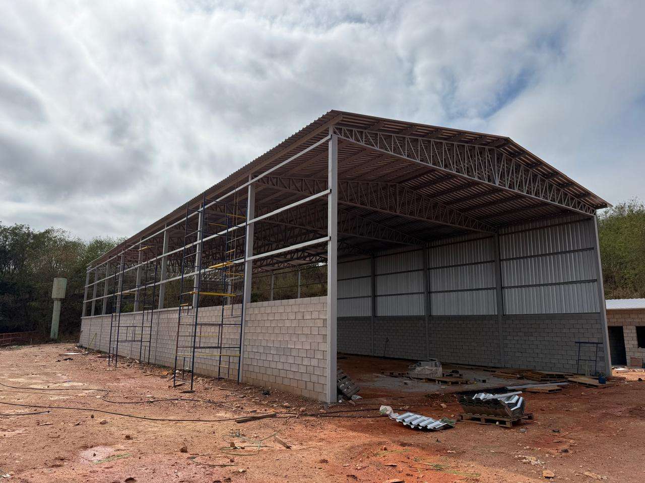 Galpão metálico com cobertura, fechamento lateral e base em alvenaria